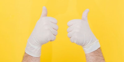 A pair of hands giving thumbs-up in surgical gloves