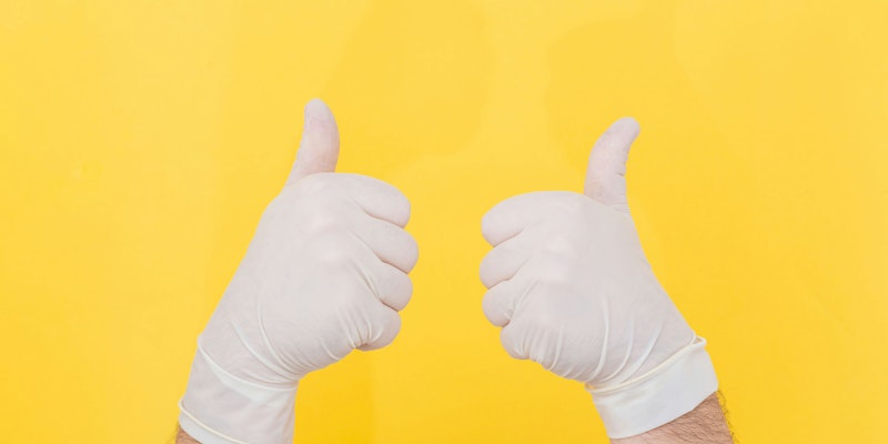 A pair of hands giving thumbs-up in surgical gloves