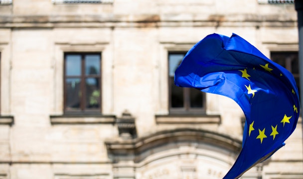 The European Union flag, waving in front of a building