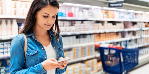 A woman shops on her mobile phone in a supermarket