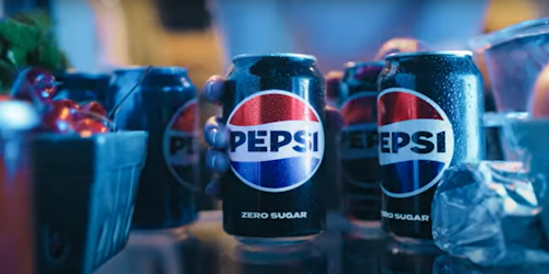 A can of Pepsi, seen from the back of a fridge, being grabbed by a hand